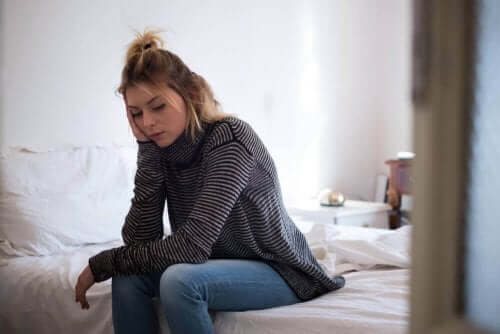 Een vrouw zit vermoeid op de rand van haar bed