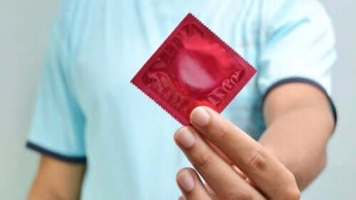 Een man houdt een condoom vast