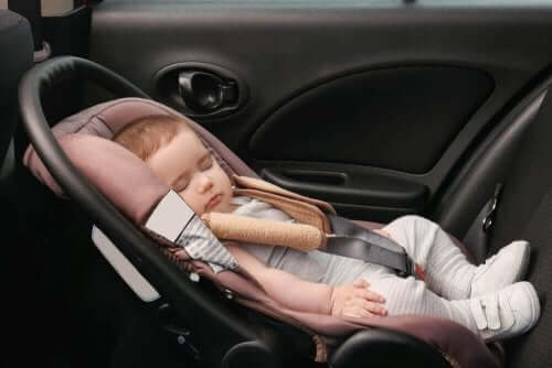Een baby slaapt in een autozitje