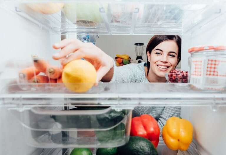 Vrouw pakt iets uit de koelkast