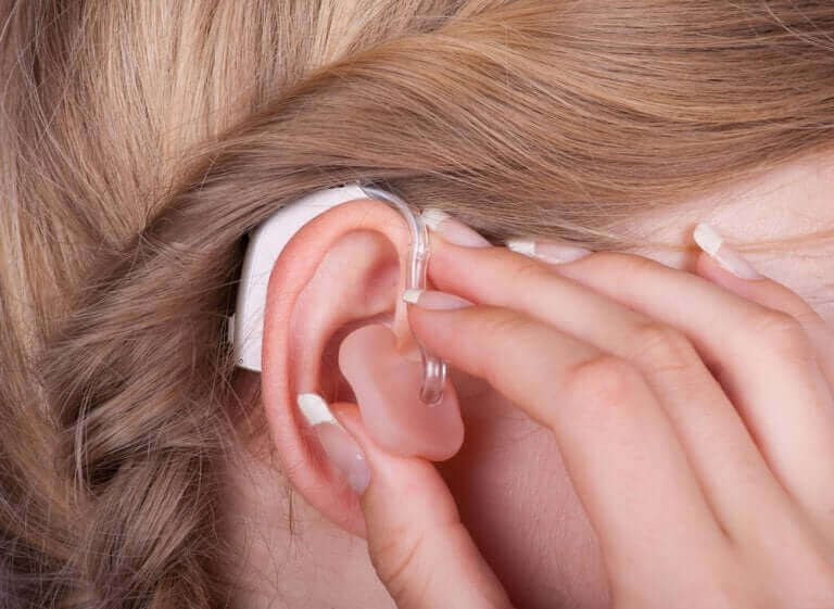 Vrouw doet gehoorapparaat in haar oor