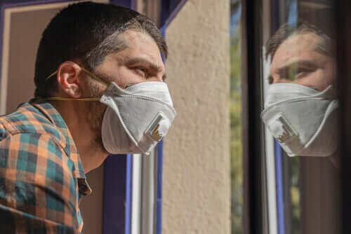 Man met angst voor het coronavirus kijkt uit het raam