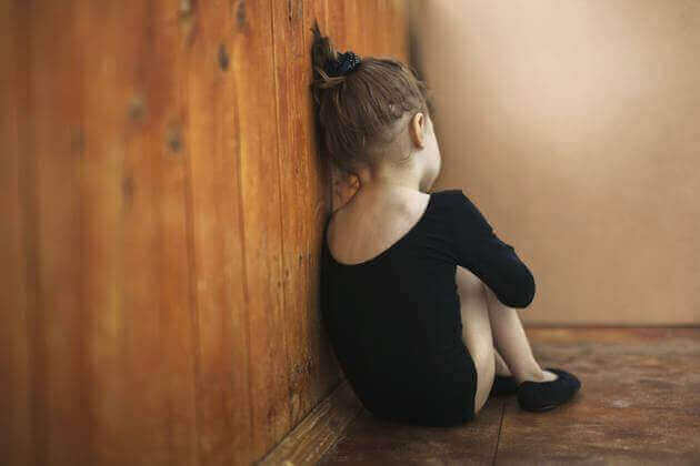 Meisje zit tegen de muur