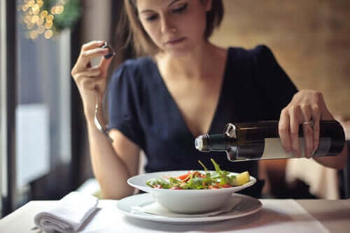 Vrouw giet olijolie op salade