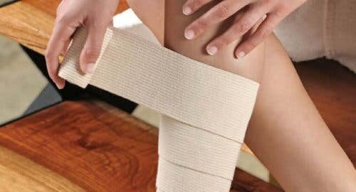 afbeelding van een persoon die zijn been in verband legt