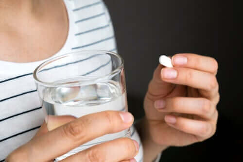 Een vrouw slikt een pil met een glas water