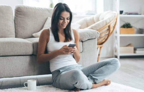 Vrouw zit op de grond met haar mobiel
