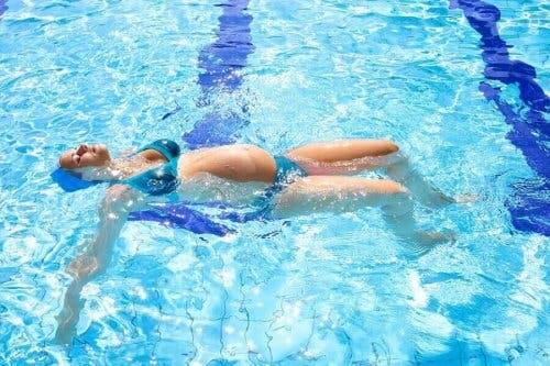 Zwangere vrouw op haar rug in het zwembad