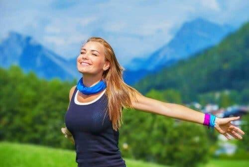 Een vrouw strekt haar armen achter zich in de buitenlucht
