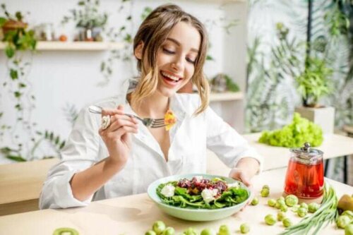 Een vrouw eet lachend een salade