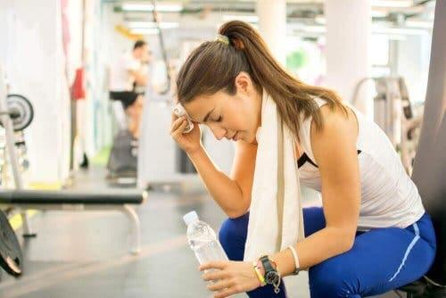 Een vrouw dept het zweet van haar voorhoofd in de sportschool