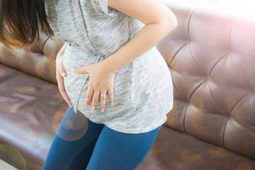 Een zwangere vrouw grijpt naar haar buik