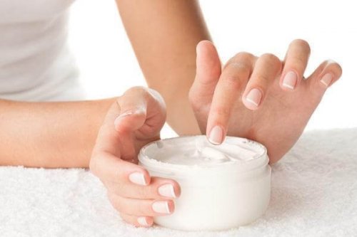 Een vrouw die wat lotion uit een potje neemt