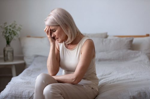 Vrouw zit met hoofdpijn op bed