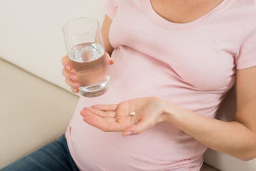 Zwangere vrouw met glas water en pil