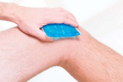 Een man die een ijspak op zijn knie aanbrengt