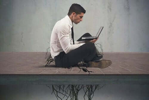 Man op laptop met wortels die hem op de grond houden