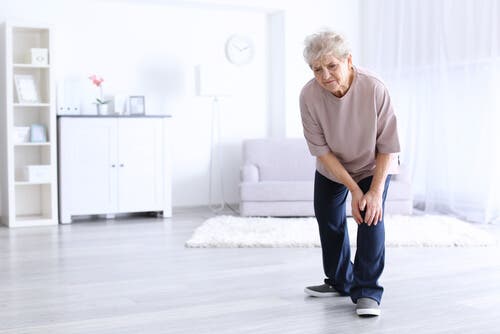 Een oudere vrouw grijpt naar haar knie