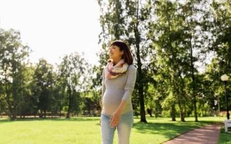 Een zwangere vrouw met een buikband wandelt in het park