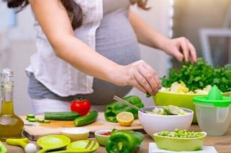 Een zwangere vrouw die een salade maakt
