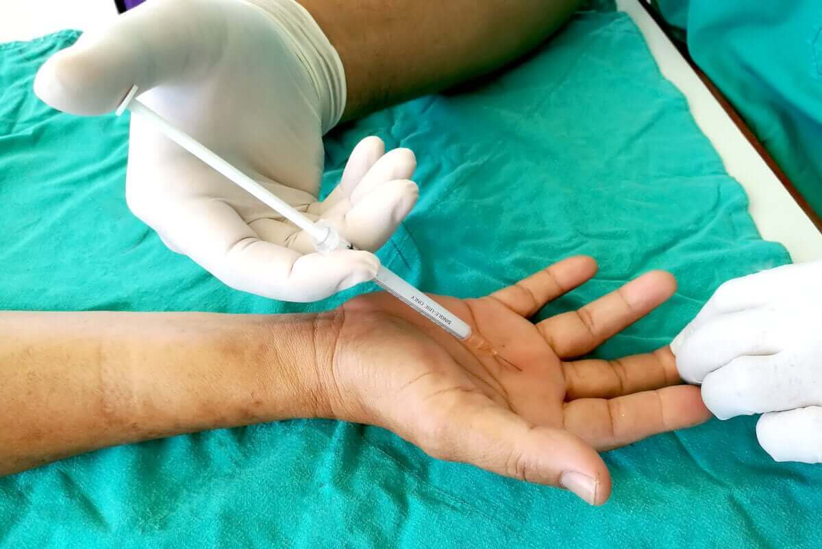 Iemand krijgt een injectie in zijn handpalm