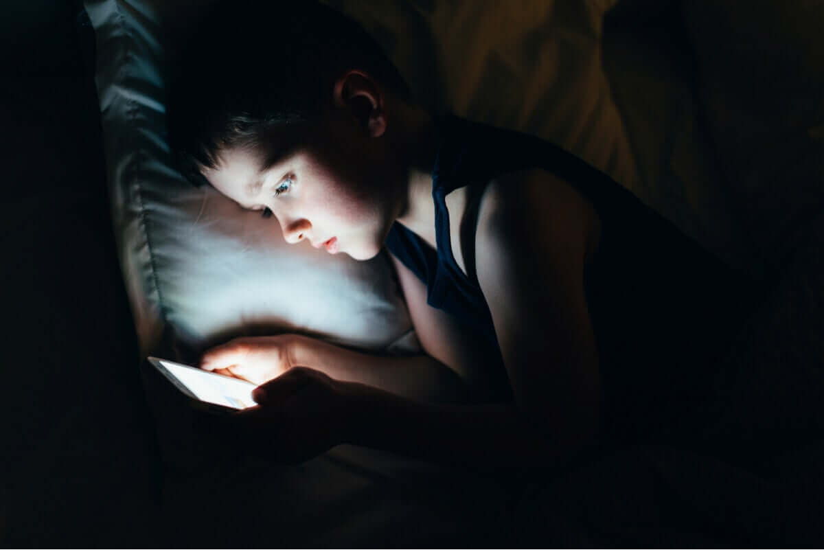 Kind zit in het donker op een tablet