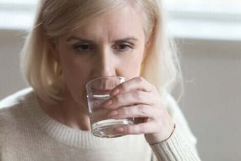 Vrouw drinkt water om menopauzaal haaruitval te verminderen