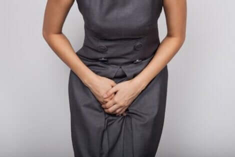 Een vrouw houdt haar handen tegen haar kruis