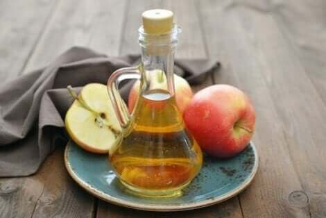 Appelazijn in een fles en verse appels op een bord