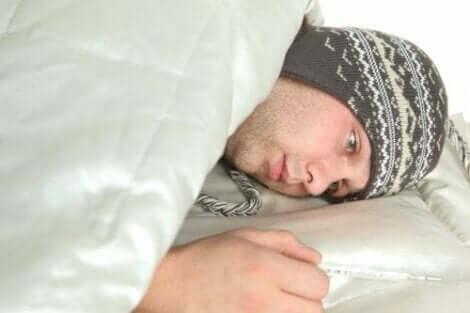 Een man ligt ziek in bed met een muts op