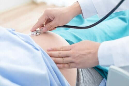 Een arts luistert met een stethoscoop naar de zwangere buik van een vrouw