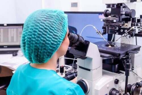 Een vrouw die door een microscoop kijkt