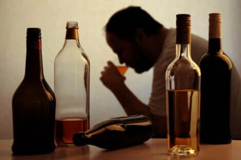 Een man drinkt een glas bier met flessen op tafel