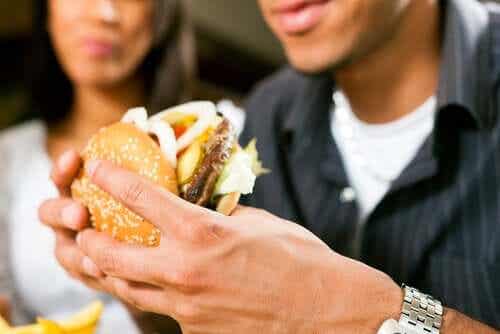 Een man eet een dubbele hamburger