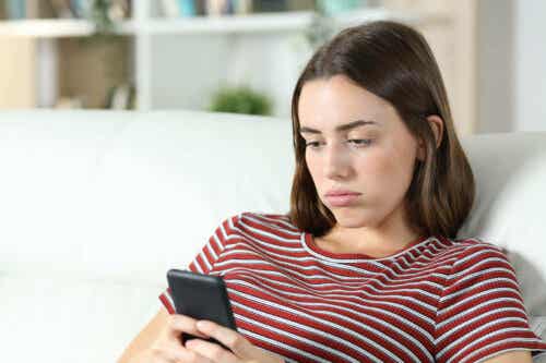 Vrouw kijkt verdrietig naar haar mobiel