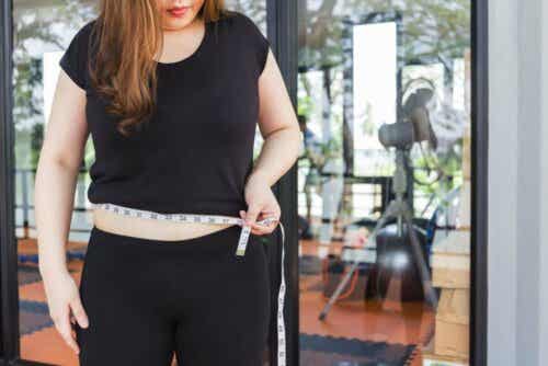 Een vrouw houdt een meetlint om haar middel