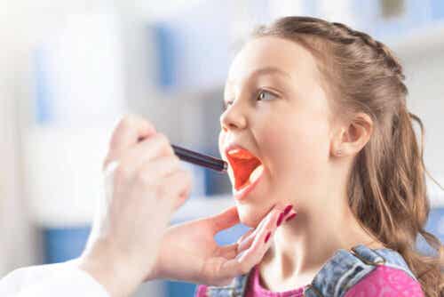 De arts onderzoekt de keel om faryngotonsillitis te diagnosticeren