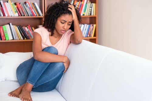 Een vrouw houdt haar hand tegen haar hoofd terwijl ze op een bank zit