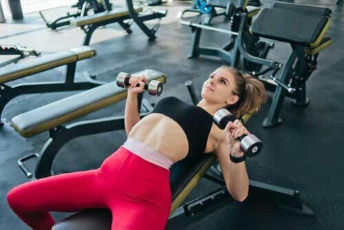 Een vrouw die gewichten heft in de sportschool