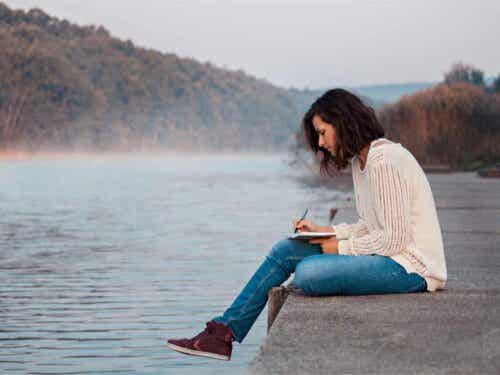 Vrouw zit bij het water te schrijven