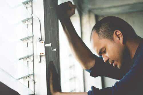 Een man leunt tegen het raam en kijkt verdrietig