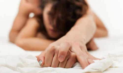 Een vrouw en een man in bed met handen verstrengeld