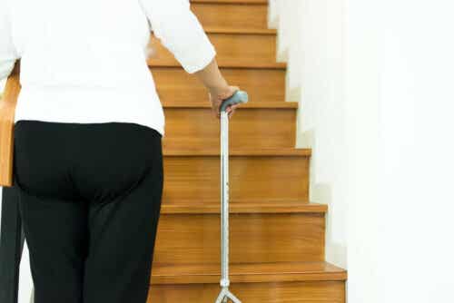 Een oudere vrouw gebruikt een wandelstok om de trap op te lopen