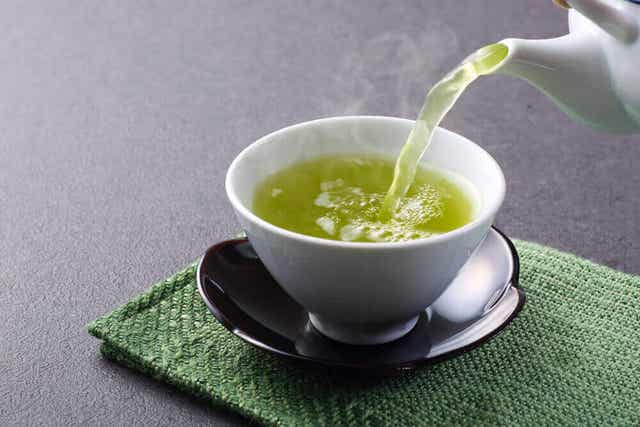 Iemand schenkt een kopje groene thee in