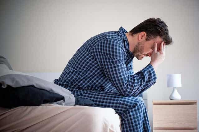 Man zit op de rand van zijn bed