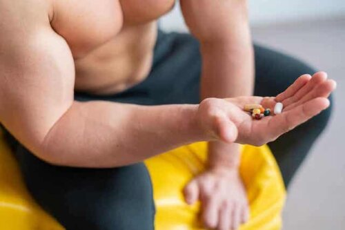 Een gespierde man houdt een aantal pillen in zijn hand