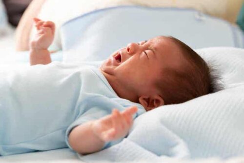 Een huilende baby ligt op zijn rug