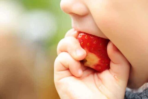 Een kind eet een aardbei