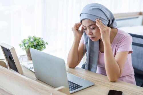 Een vrouw wrijft haar handen tegen haar hoofd terwijl ze naar een computerscherm kijkt