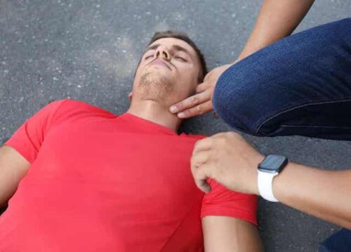 Een man controleert de polsslag van iemand die op de grond ligt
